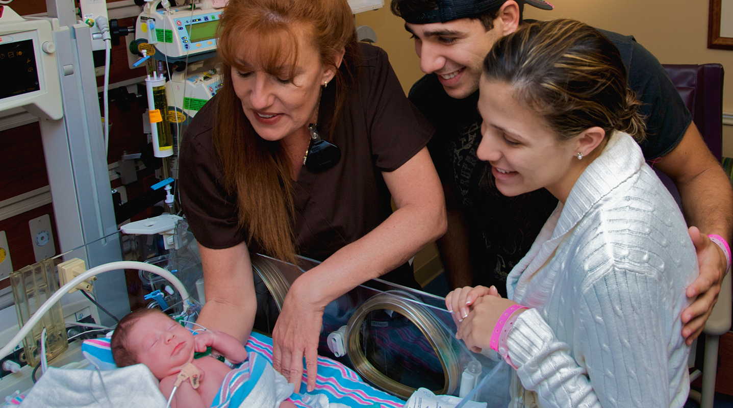 parents, nurse looking at baby in NICU